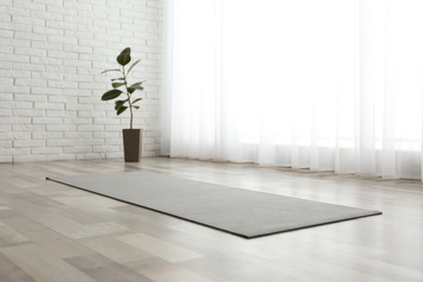 Unrolled grey yoga mat on floor in room