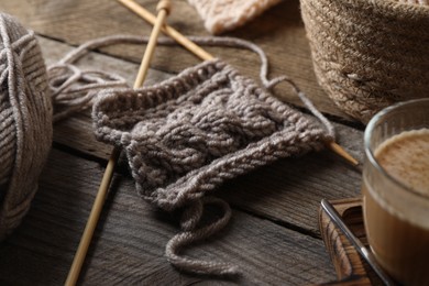 Photo of Grey knitting and needles on wooden table, closeup
