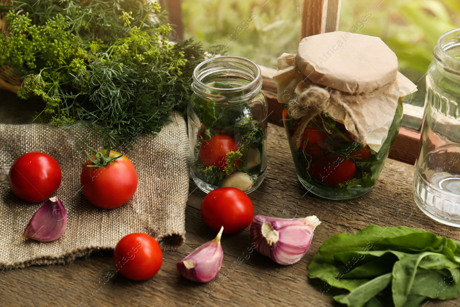 Photo of Glass jars, fresh vegetables and herbs on wooden table indoors. Pickling recipe