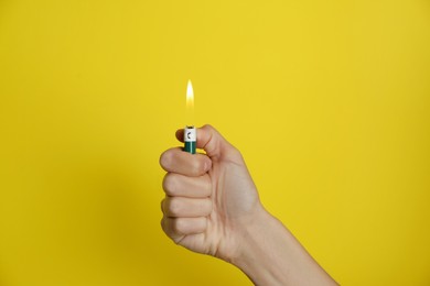 Photo of Woman holding green lighter on yellow background, closeup