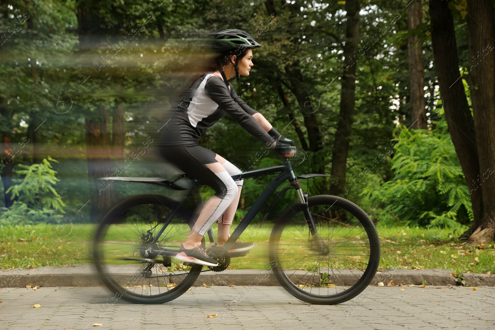 Image of Young woman riding bicycle on street. Motion blur effect showing her speed