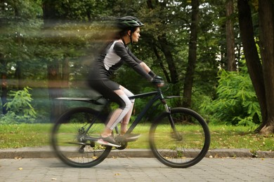 Young woman riding bicycle on street. Motion blur effect showing her speed