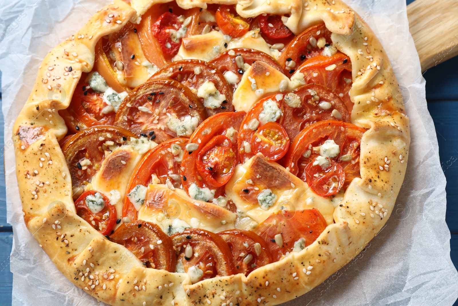 Photo of Tasty galette with tomato and cheese (Caprese galette) on blue table, closeup