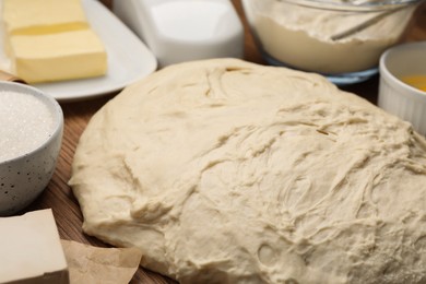 Fresh yeast dough and ingredients for cake on wooden table, closeup