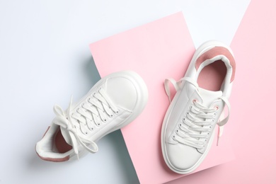 Stylish sneakers with white shoe laces on color background, flat lay
