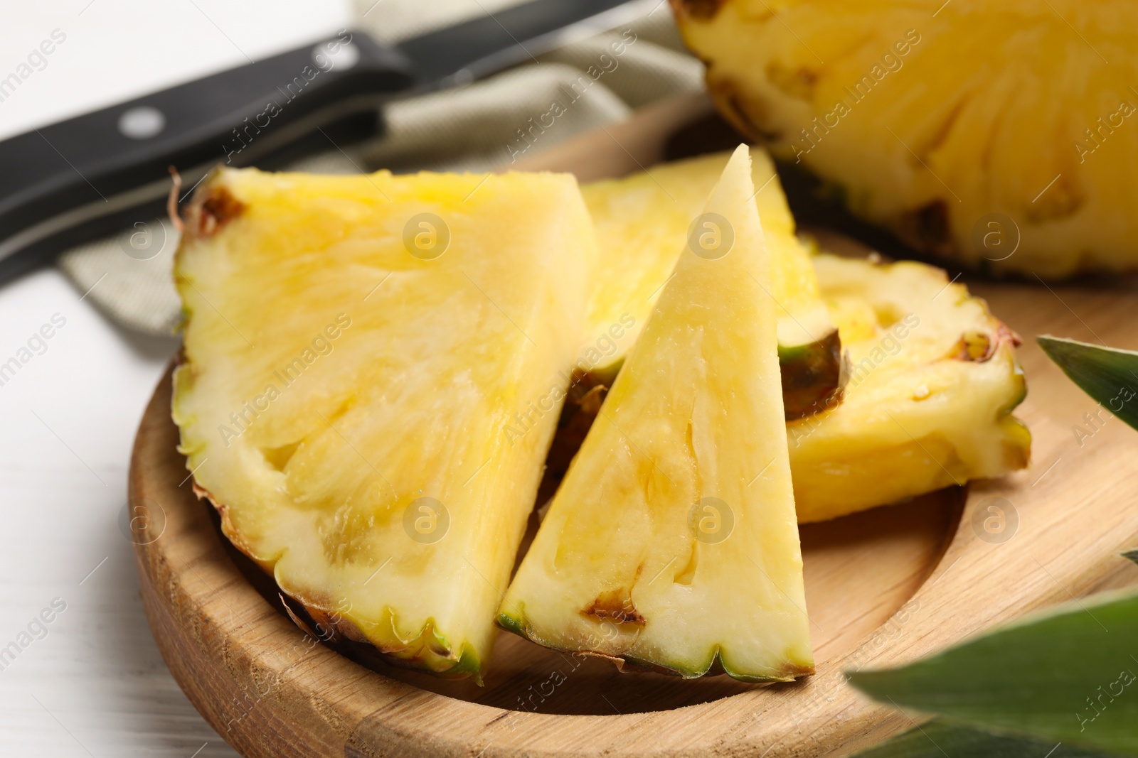 Photo of Slices of ripe juicy pineapple and knife on white wooden table, closeup