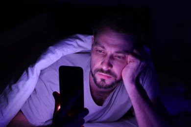 Man using smartphone in bed at night. Internet addiction