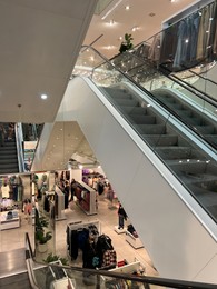 Photo of Warsaw, Poland - July 26, 2022: Big shopping mall with escalator and fashion stores inside