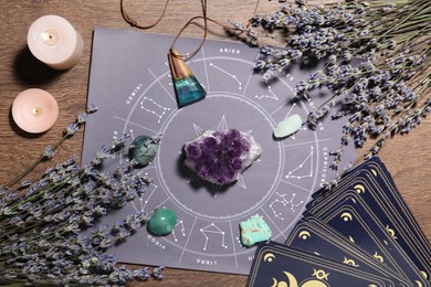 Photo of Astrology prediction. Zodiac wheel, gemstones, tarot cards and burning candles on wooden table, flat lay