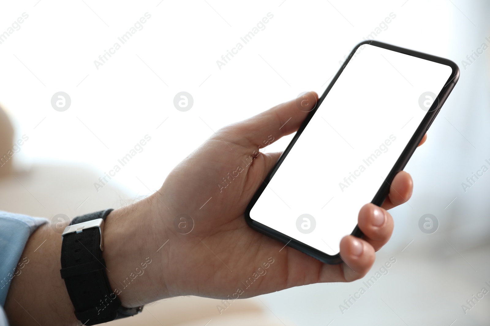 Image of Man holding mobile phone with empty screen indoors, closeup