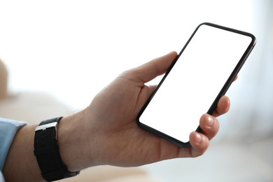 Image of Man holding mobile phone with empty screen indoors, closeup