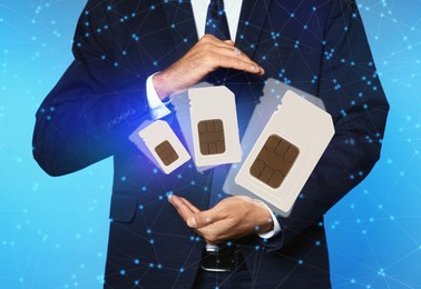 Man demonstrating SIM cards of different sizes on blue background, closeup 