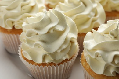 Photo of Tasty vanilla cupcakes with cream on plate, closeup