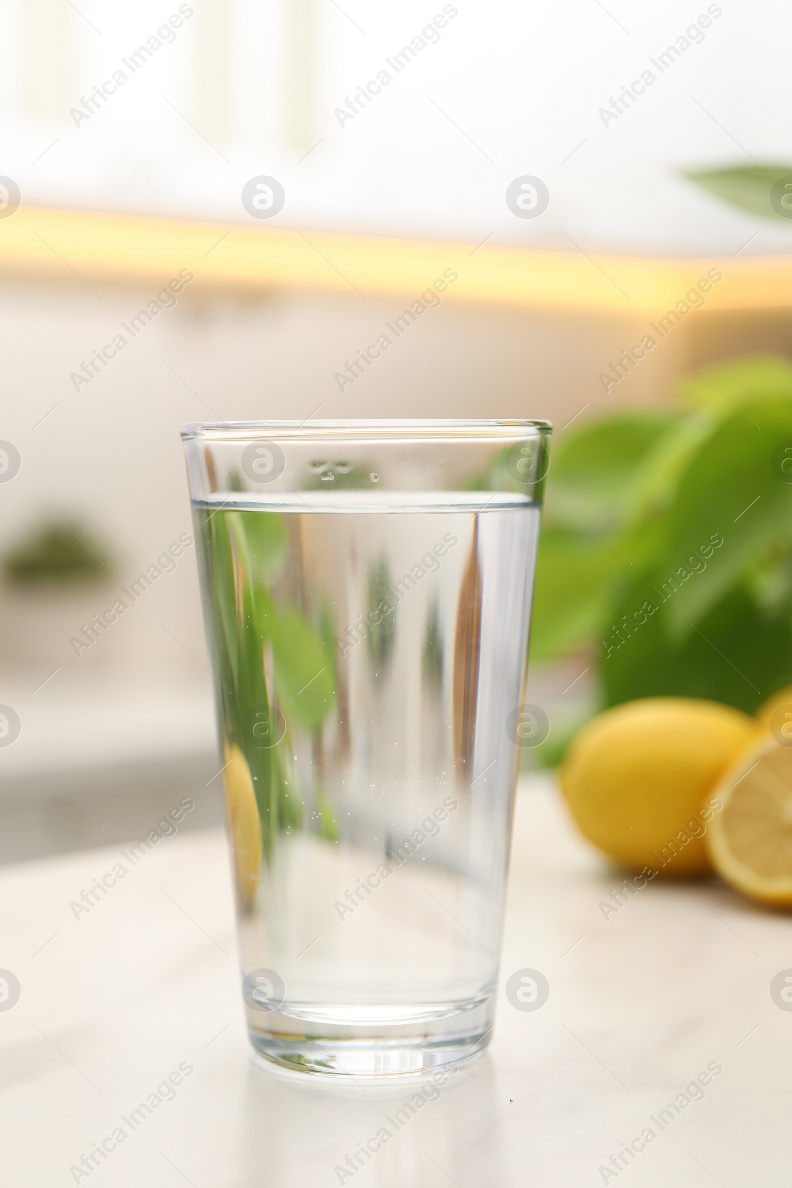 Photo of Glass with clear water on white table in kitchen