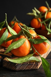 Photo of Wooden board with ripe tangerines on table