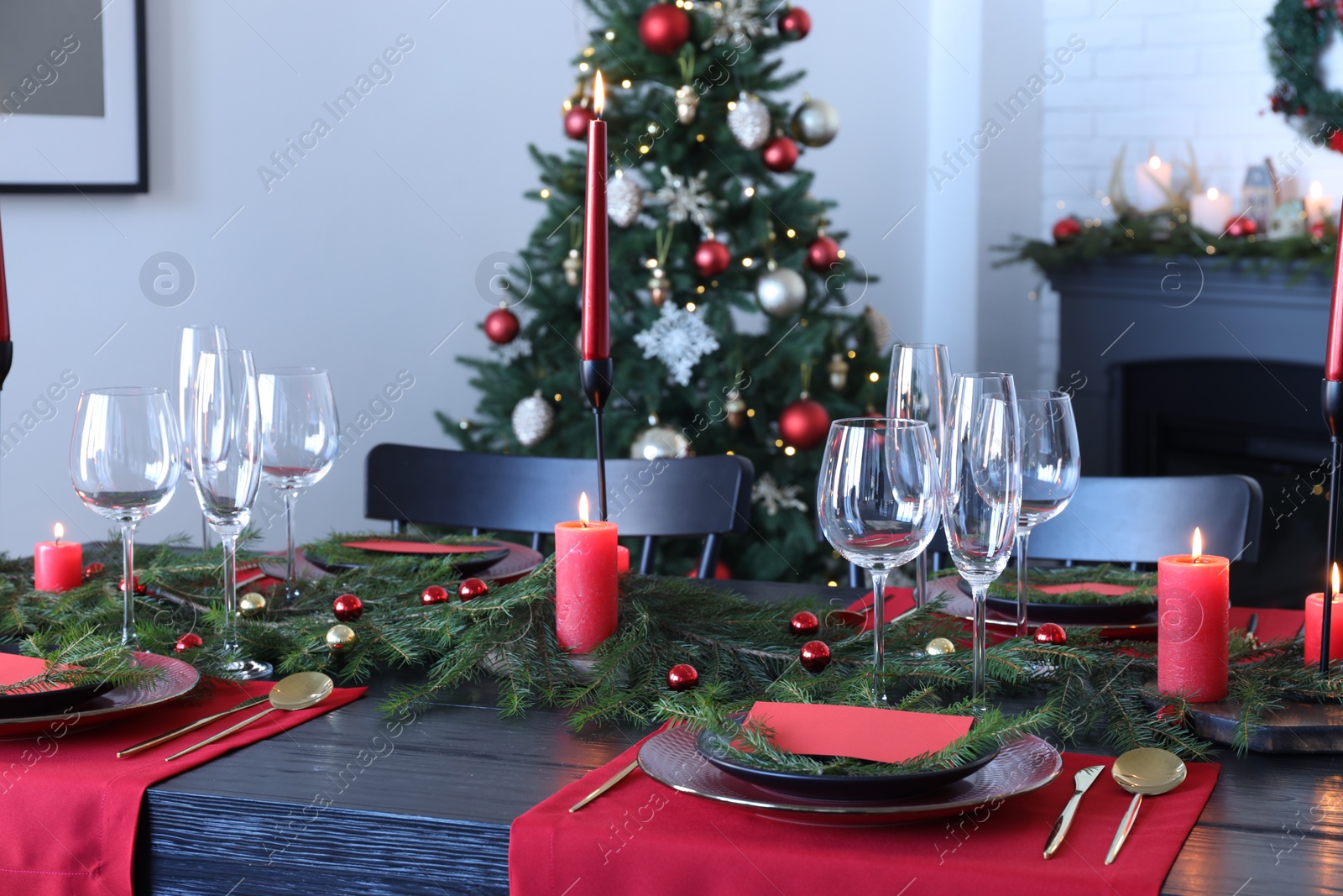 Photo of Elegant Christmas table setting with dishware and burning candles in festively decorated room