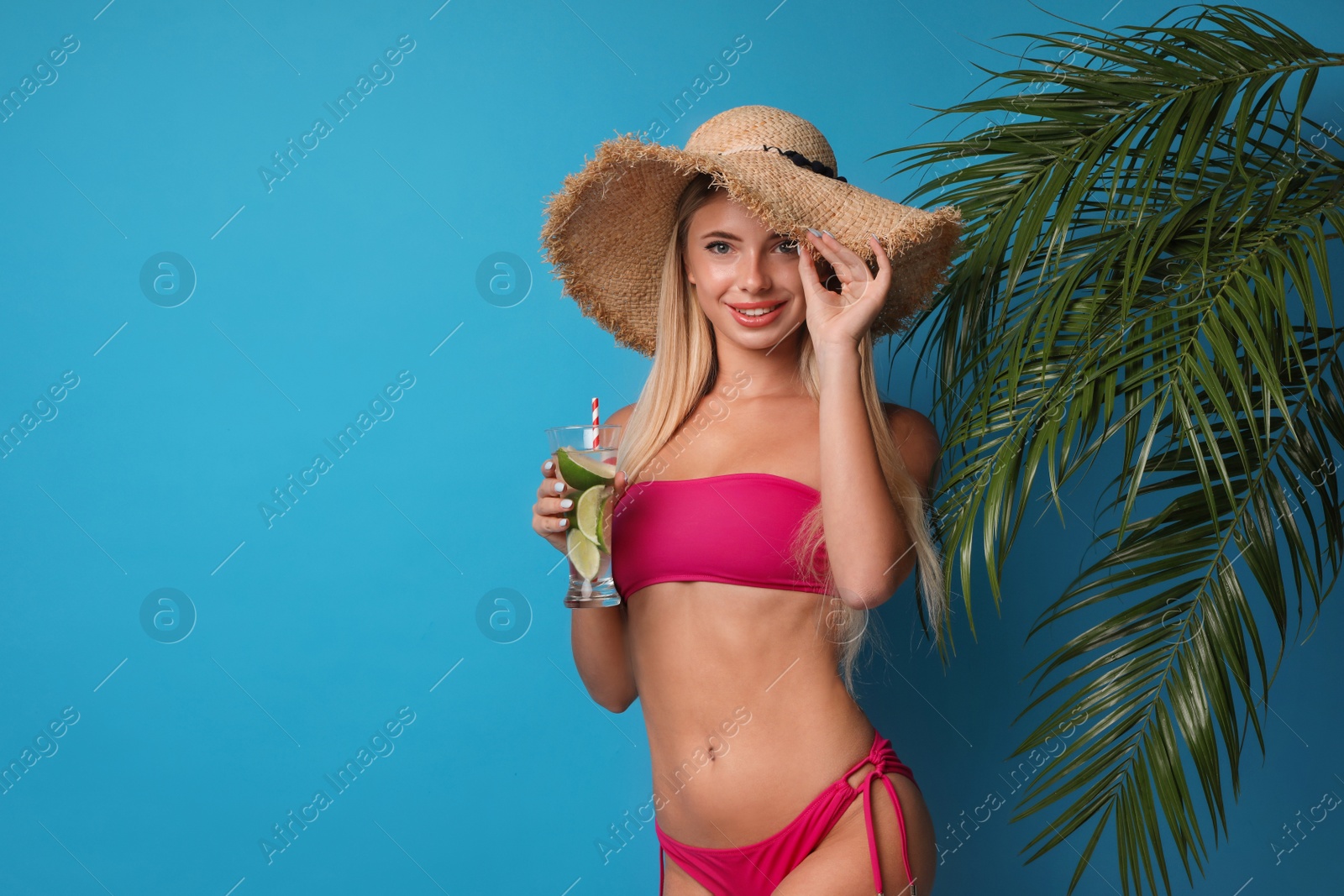 Photo of Pretty young woman wearing stylish bikini with cocktail on blue background. Space for text