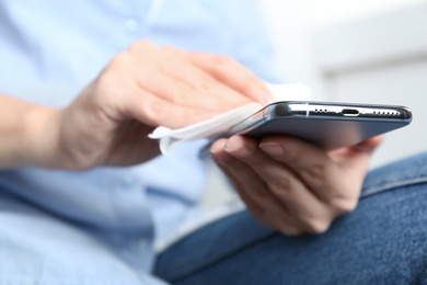 Photo of Woman cleaning smartphone with antiseptic wipe, closeup