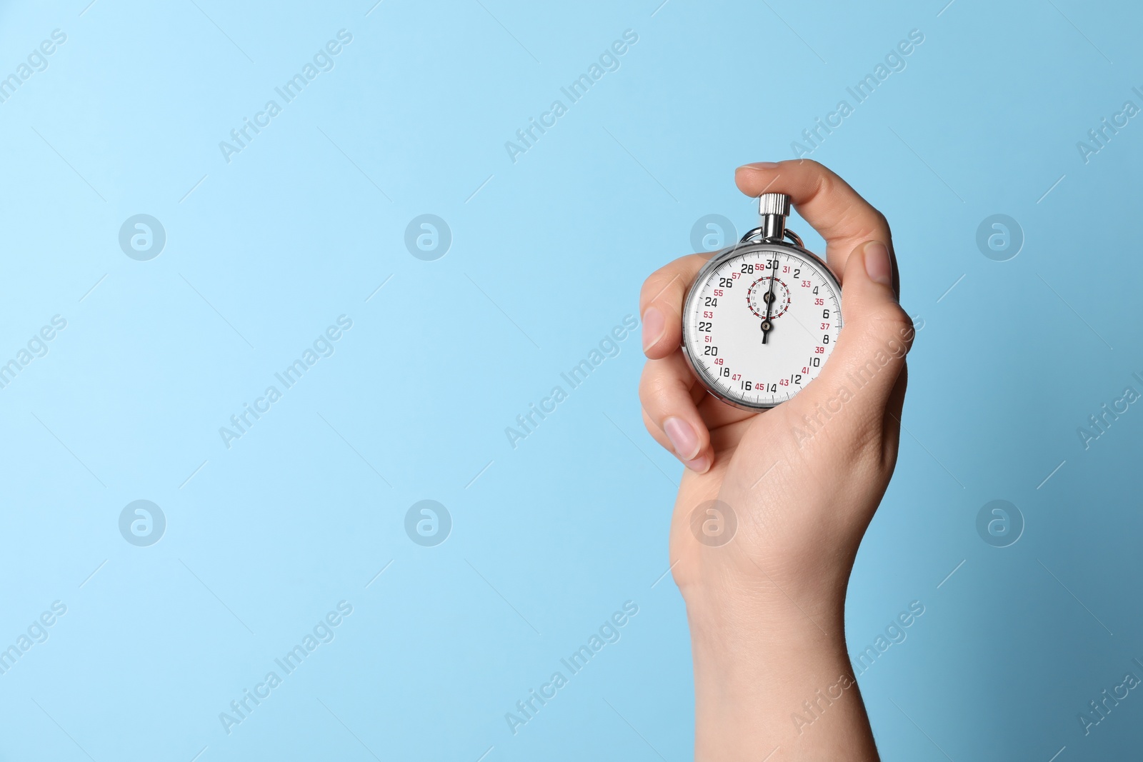 Photo of Woman holding vintage timer on light blue background, closeup. Space for text