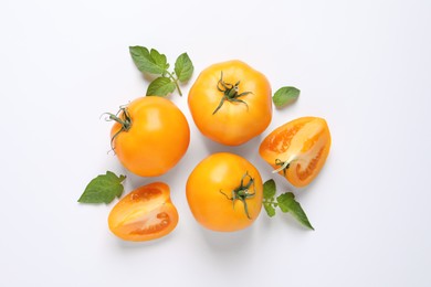 Photo of Cut and whole ripe yellow tomatoes with leaves on white background, top view