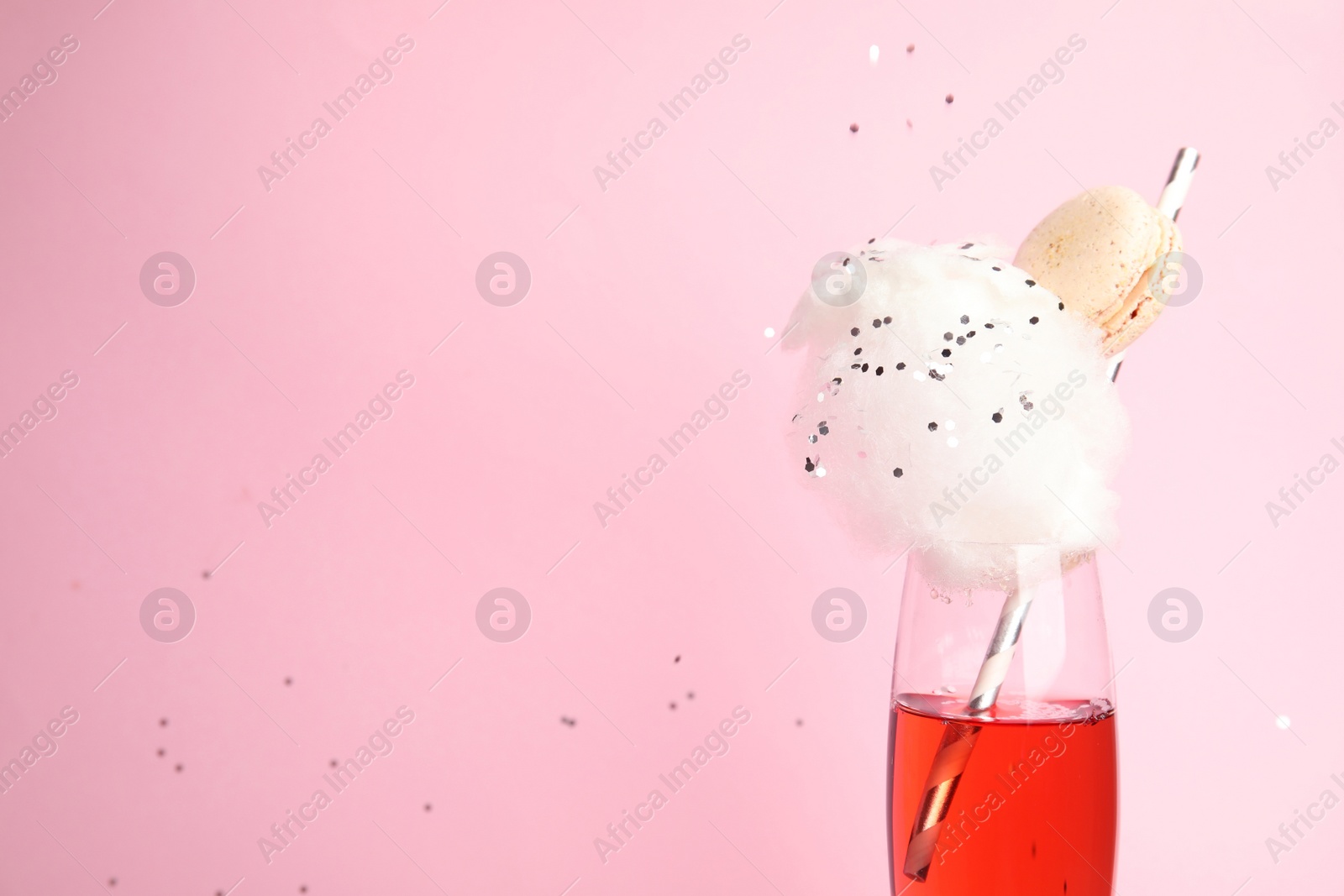 Photo of Cocktail with cotton candy in glass on pink background, space for text