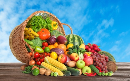Image of Assortment of fresh organic fruits and vegetables on wooden table outdoors 