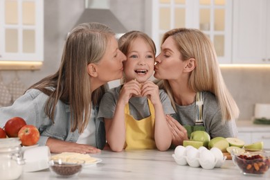 Photo of Three generations. Grandmother, her daughter and granddaughter in kitchen