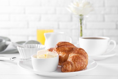 Fresh croissant and butter on white wooden table. Tasty breakfast