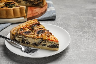 Photo of Piece of delicious quiche with mushrooms served on light grey table. Space for text