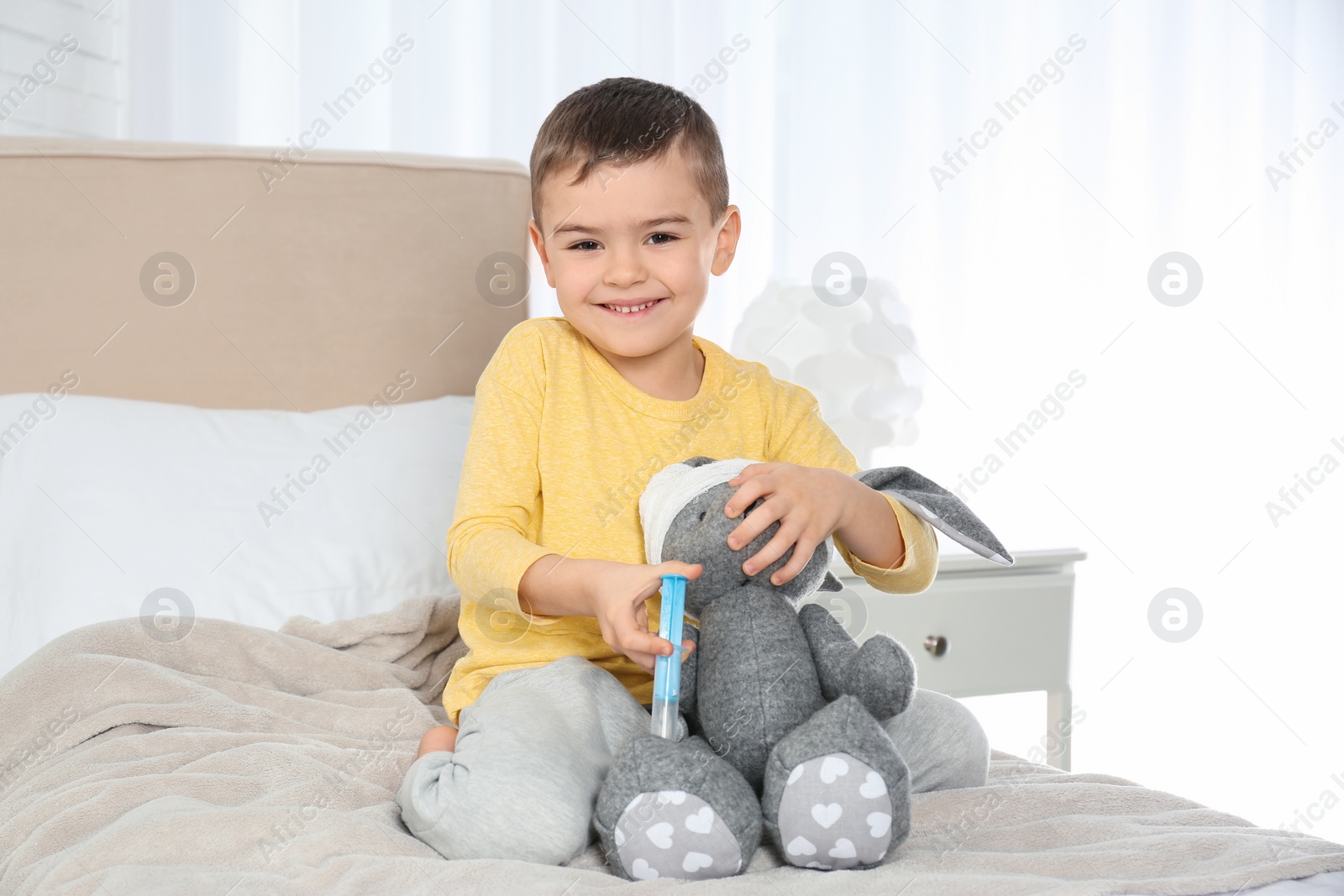 Photo of Cute child playing doctor with stuffed toy at hospital