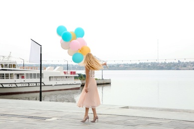 Photo of Beautiful young woman with bunch of balloons outdoors