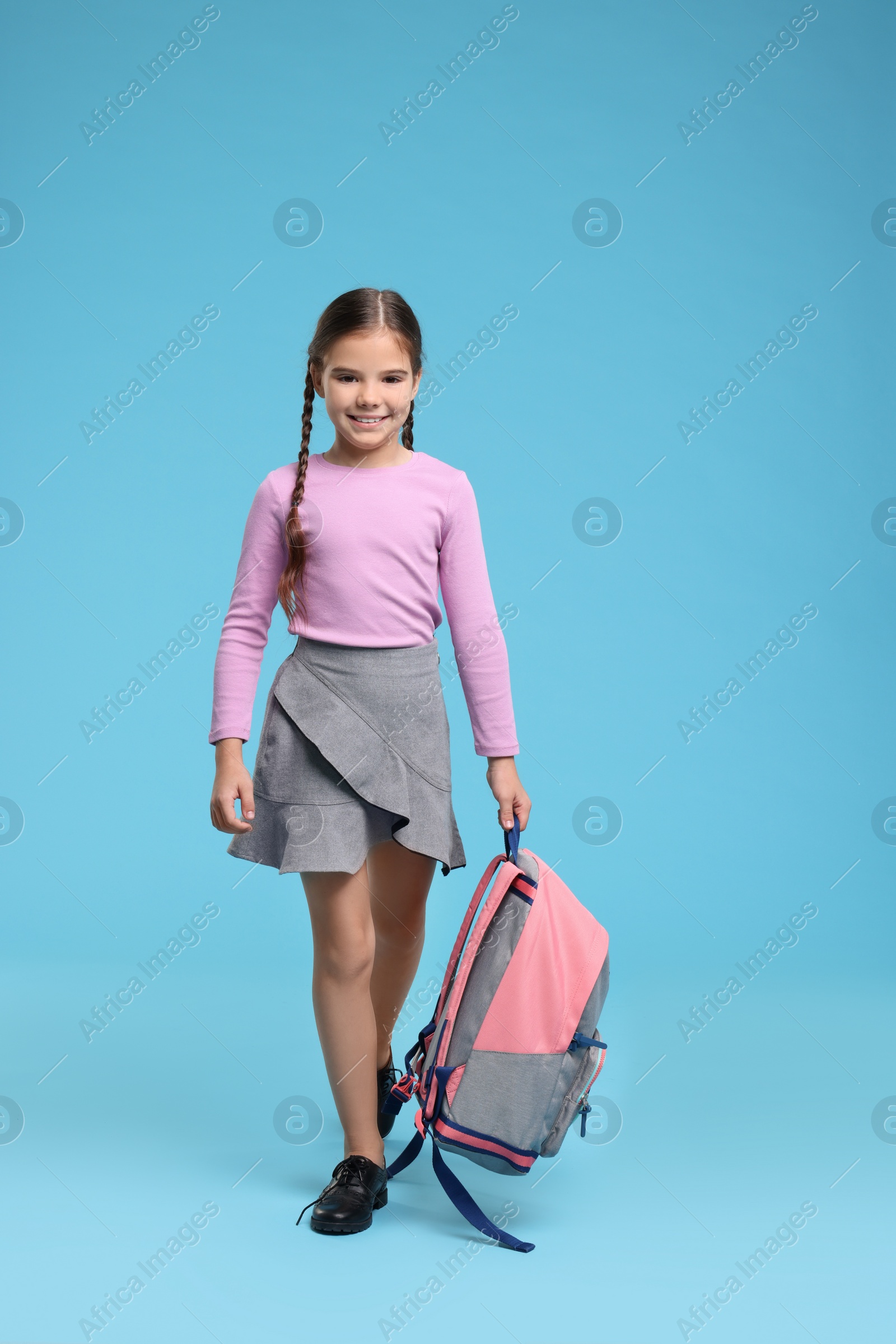 Photo of Back to school. Cute girl with backpack on light blue background