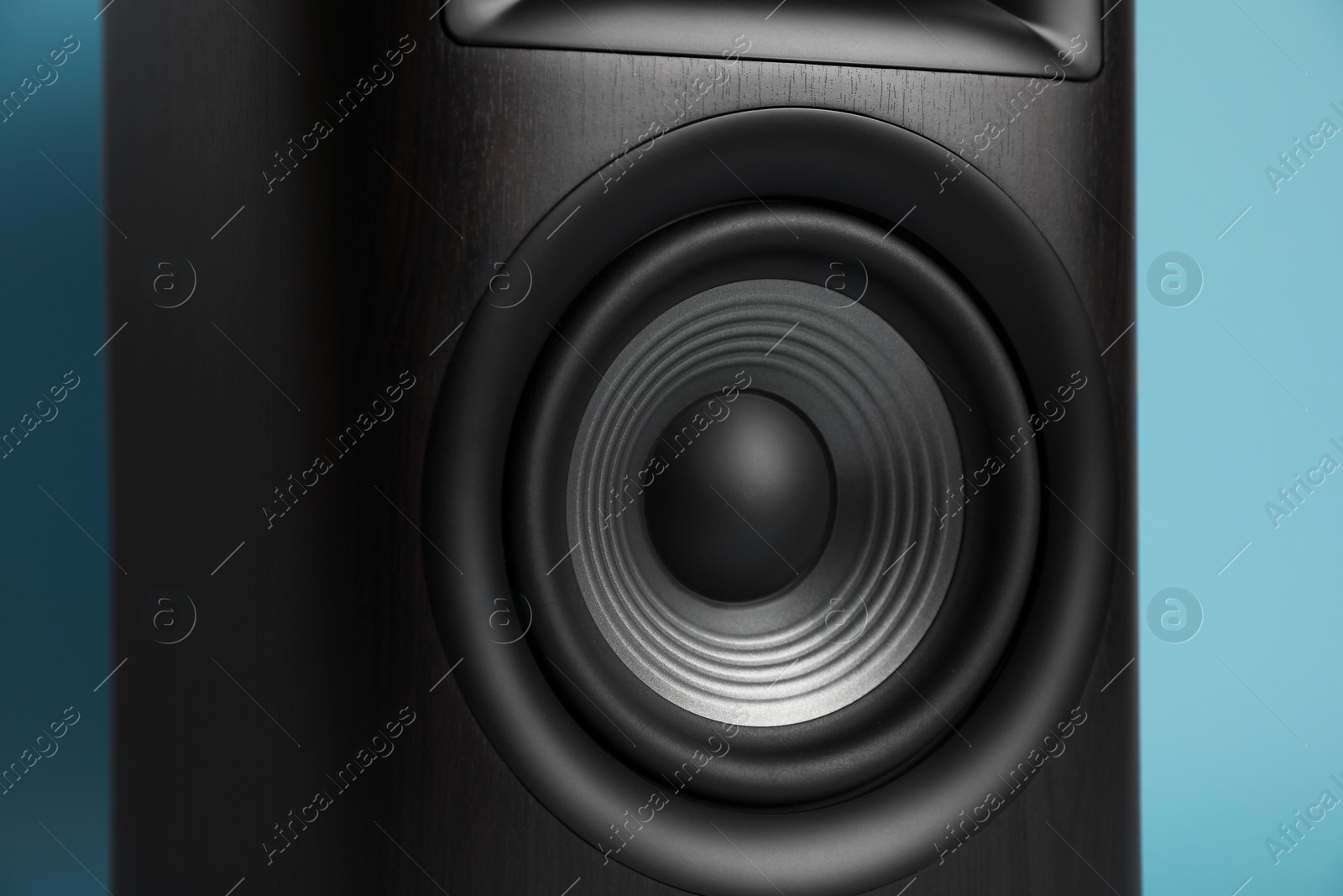 Photo of One wooden sound speaker on light blue background, closeup