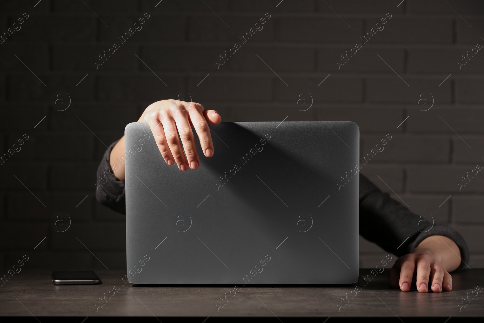 Photo of Woman lying on laptop at table in dark room. Loneliness concept