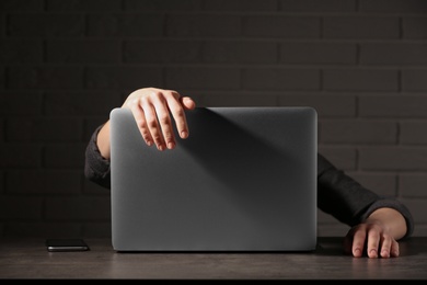 Photo of Woman lying on laptop at table in dark room. Loneliness concept