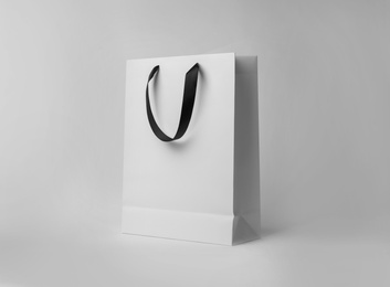 Photo of Paper shopping bag with ribbon handles on white background. Mockup for design