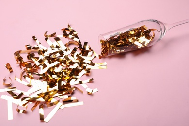 Glass and shiny confetti on pink background