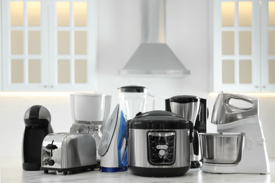 Photo of Set of modern home appliances on white marble table in kitchen