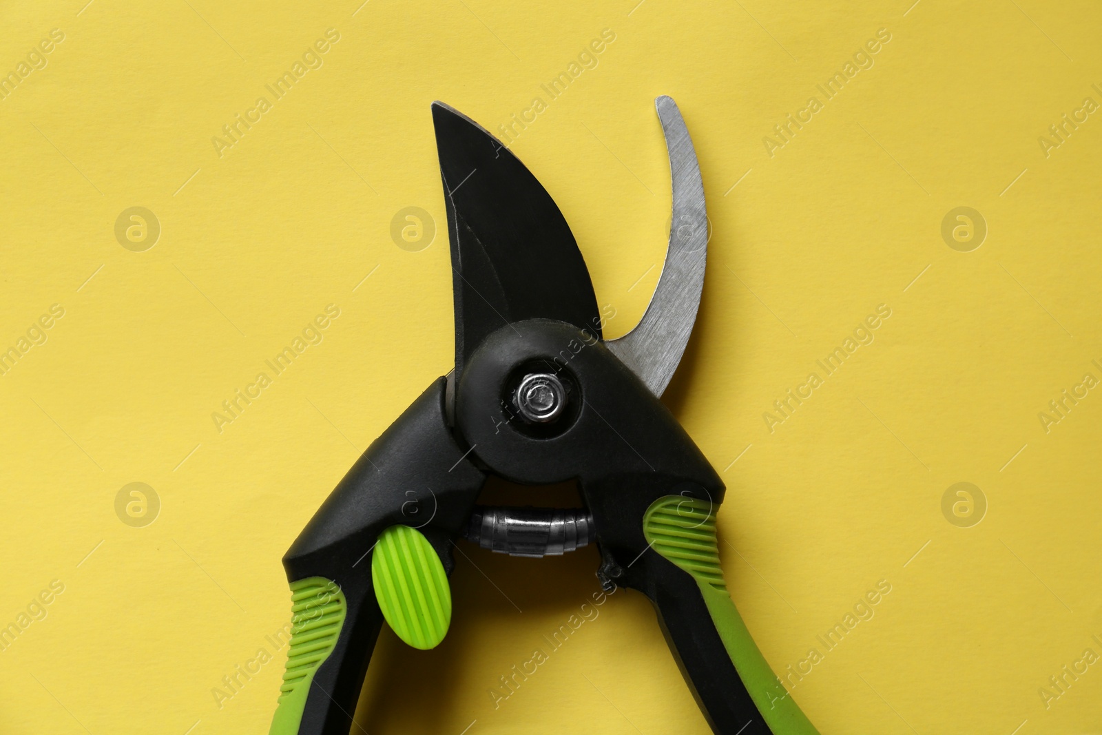 Photo of Secateur on light yellow background, top view