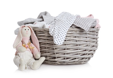 Photo of Wicker basket with baby clothes and bunny on white background