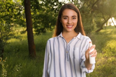 Woman with insect repellent spray in park. Tick bites prevention