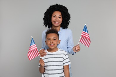 4th of July - Independence Day of USA. Happy woman and her son with American flags on light grey background