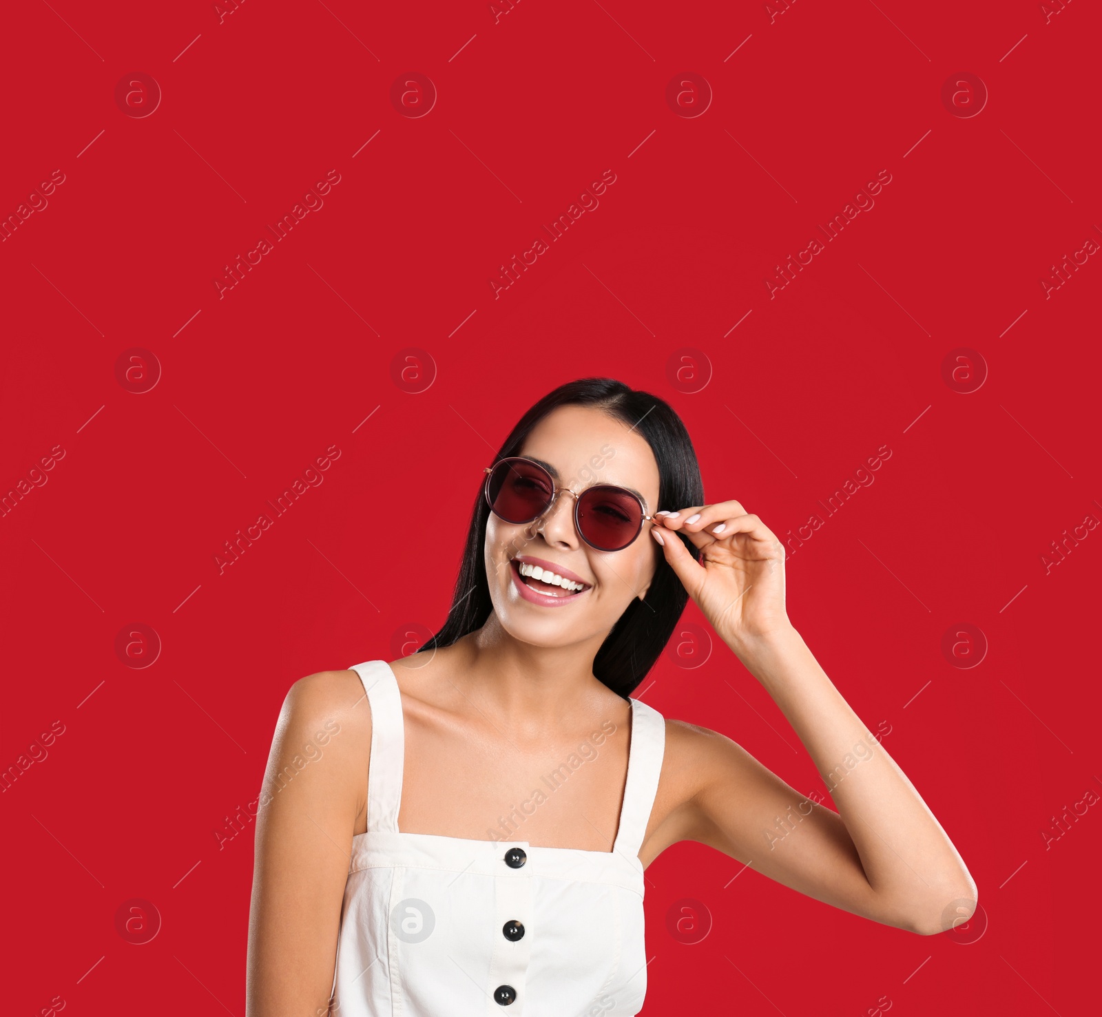 Photo of Beautiful woman wearing sunglasses on red background