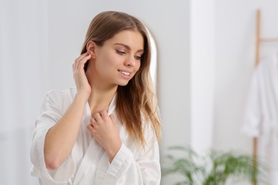 Photo of Beautiful happy woman wearing stylish white robe in bathroom. Space for text