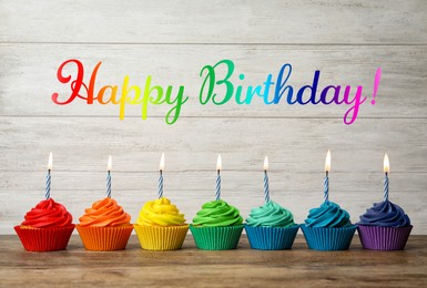 Image of Happy Birthday! Delicious cupcakes with burning candles on wooden table
