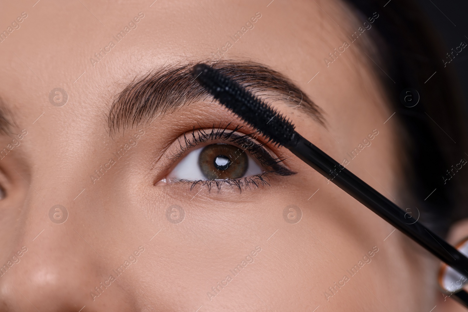 Photo of Beautiful young woman applying mascara, closeup view