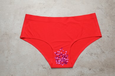Photo of Woman's panties with pink sequins on grey background, top view. Menstrual cycle