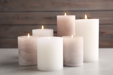Photo of Set of different burning candles on light grey stone table