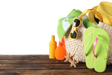 Photo of Bag with different beach objects on wooden table against white background. Space for text