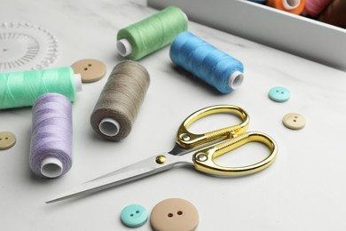 Photo of Sewing threads, scissors and buttons on white marble table